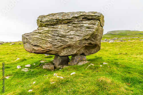 A side view showing a glacial erratic supported on the limestone pavement on the southern slopes of Ingleborough, Yorkshire, UK in summertime photo