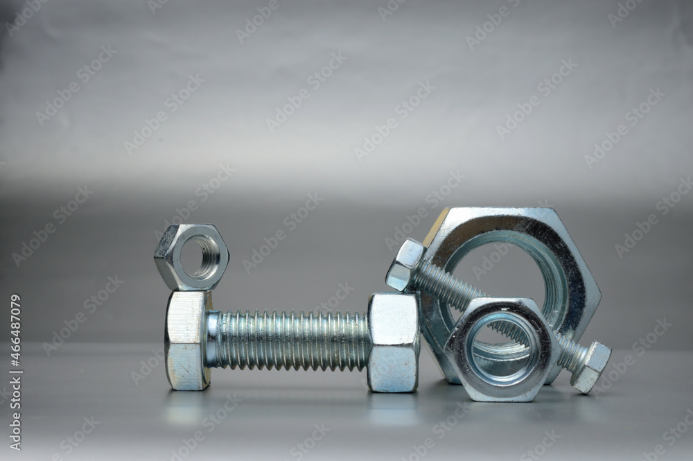 composition of new bolts and nuts of different sizes on a gray background. composition of new bolts and nuts of different sizes on a gray background.