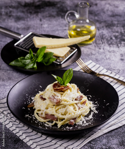 Pasta Carbonara. Spaghetti with bacon, parsel and parmesan cheese. Pasta Carbonara on black plate with parmesan. Italian food. photo