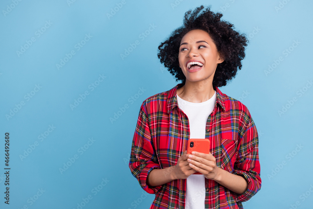 Photo of young african girl happy positive smile use cellphone look empty space isolated over blue color background Photo of young african girl happy positive smile use cellphone look empty space isolated over blue color background