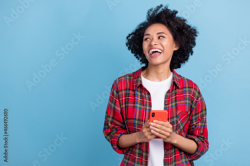 Photo of young african girl happy positive smile use cellphone look empty space isolated over blue color background