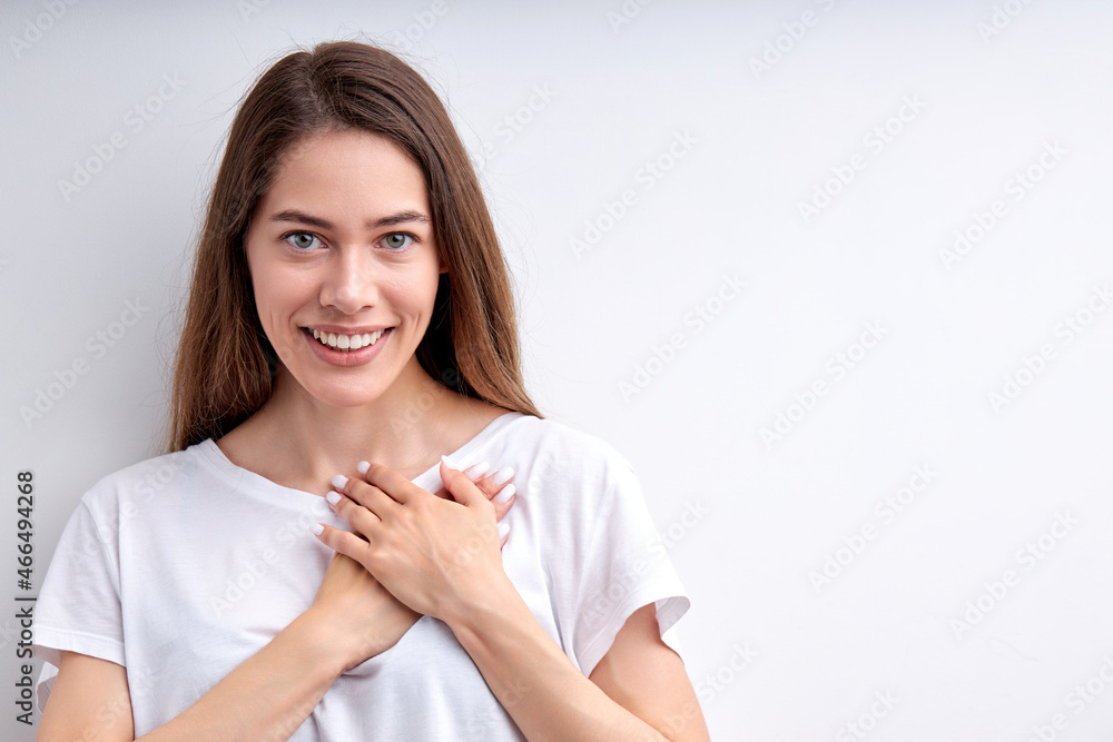 Attractive happy woman expressing gratitude, holding hands on chest, thankful for everything, looking at camera having nice smile, casually dressed. isolated on white studio background, copy space Attractive happy woman expressing gratitude, holding hands on chest, thankful for everything, looking at camera having nice smile, casually dressed. isolated on white studio background, copy space
