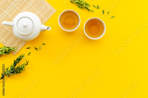 Tea drinking with white teapot and two cups with green leaves  top view