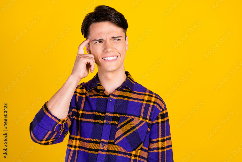 Photo of upset unhappy teen boy wear plaid outfit finger temple looking empty space isolated yellow color background Photo of upset unhappy teen boy wear plaid outfit finger temple looking empty space isolated yellow color background