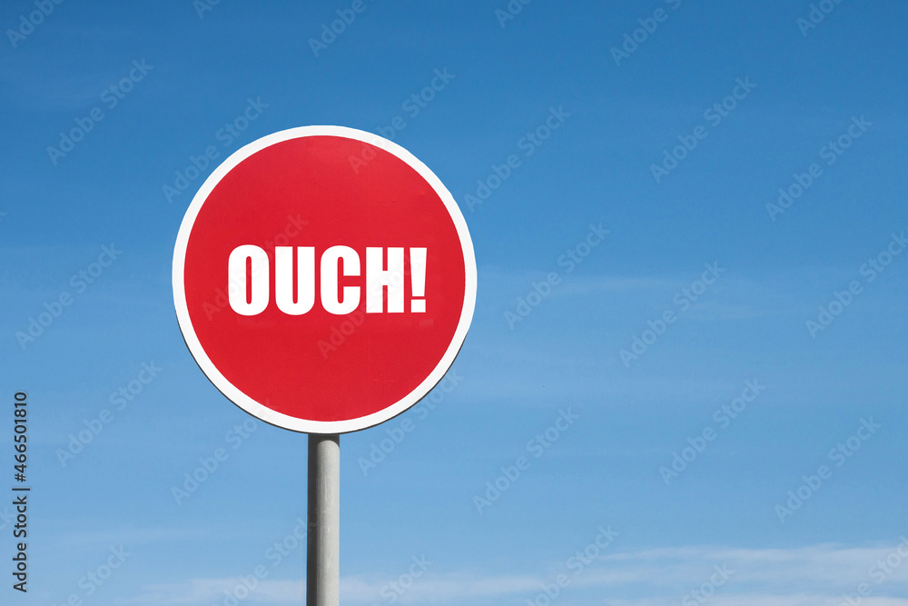 Ouch sign in a round red frame against a blue sky Ouch sign in a round red frame against a blue sky