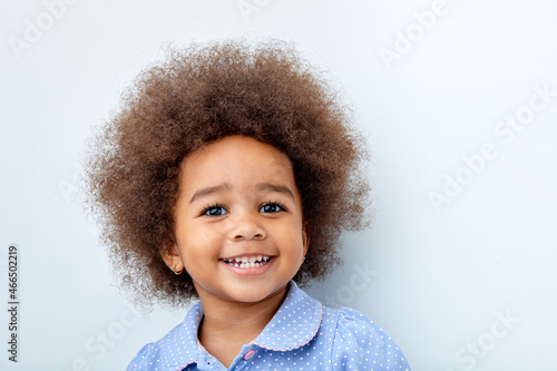 Close-up portrait of african child girl laughing, smiling, looking at camera. beautiful black kid with curly hair having fun, excited, having good mood. isolated on white studio background
