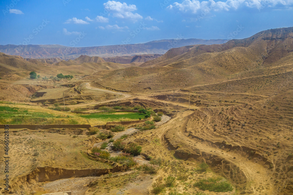 Semi-dry river, winding between hills in the middle of an almost deserted area. The mountains of the Gissar ridge are visible in the distance. Shot in the Surkhandarya region of southern Uzbekistan