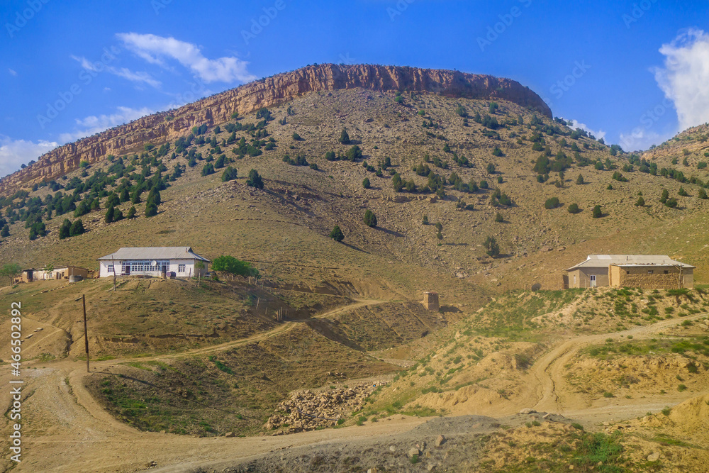 Houses in the countryside at the foot of a hill turning into a mountain plateau. Shot in the Surkhandarya region in Uzbekistan near the mountains of the Gissar ridge