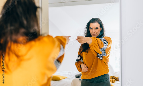 Self confident single woman pointing finger at reflection in mirror dancing and felling good. Independent person with high self esteem talk positive I can do it motivation. 