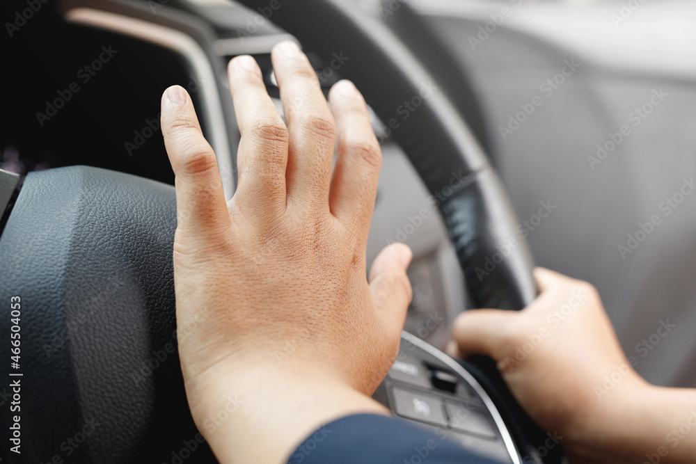 person pushing horn while driving sitting of a steering wheel press car, honking sound to warn other people in traffic concept.