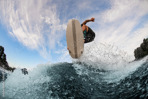 beautiful view of a wakesurf board and man jumping in the air above a splashing wave photo