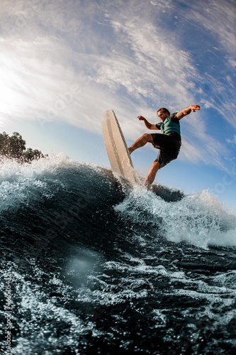 Sporting energy wakeboarder performs various extreme tricks on high splashing river wave © fesenko