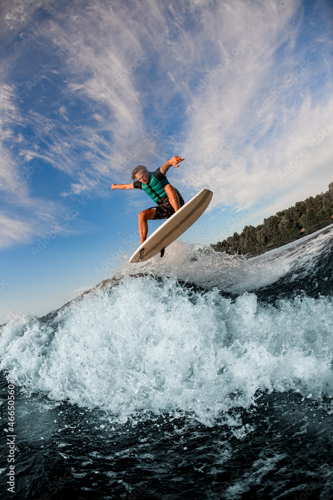 amazing view of man flying in the air on wakesurf over splashing wave
