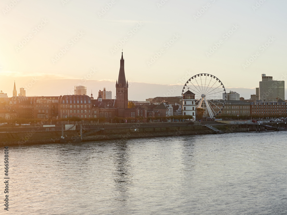 Fototapeta premium Panorama view of the city of Dusseldorf from the Rhine in Germany. Skyline of the old town with Ferris wheel at sunrise.