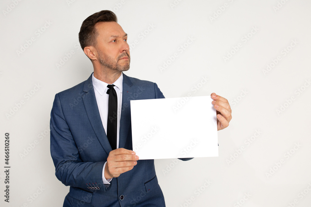Young handsome man in bussines suit with beard holding empty paper blank in hand on white background, looking to side, Young handsome man in bussines suit with beard holding empty paper blank in hand on white background, looking to side,