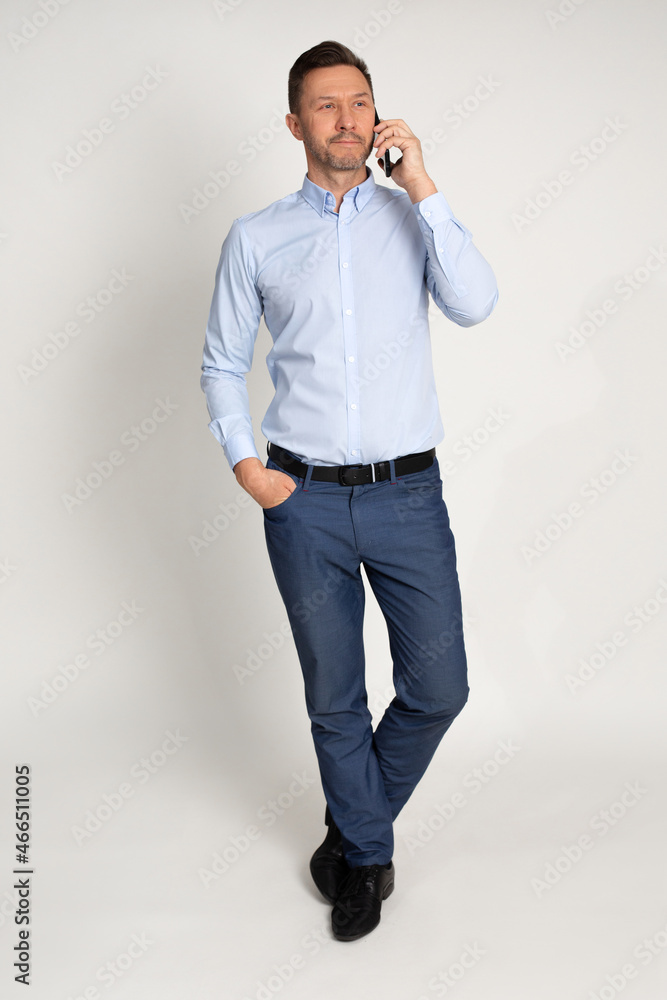 full-length portrait of businessman in elegant clothes in studio on neutral background uses smartphone, emotionally talking on phone full-length portrait of businessman in elegant clothes in studio on neutral background uses smartphone, emotionally talking on phone
