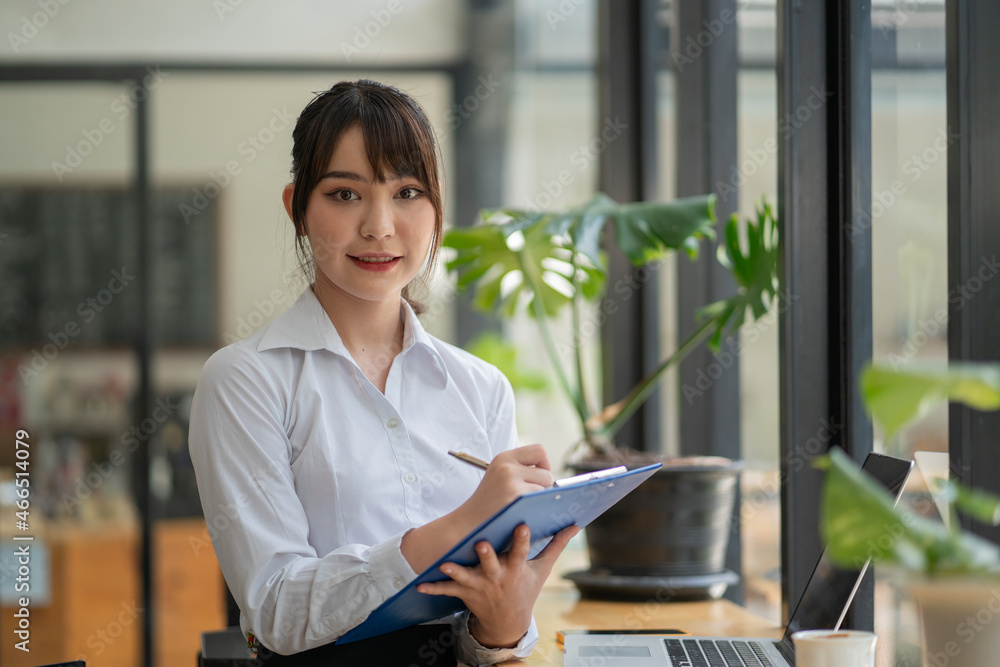 Asian young female executive reading a document in her hands while working at the office. Asian young female executive reading a document in her hands while working at the office.
