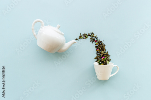 Tea background o white teapot and cup with dry tea leaves