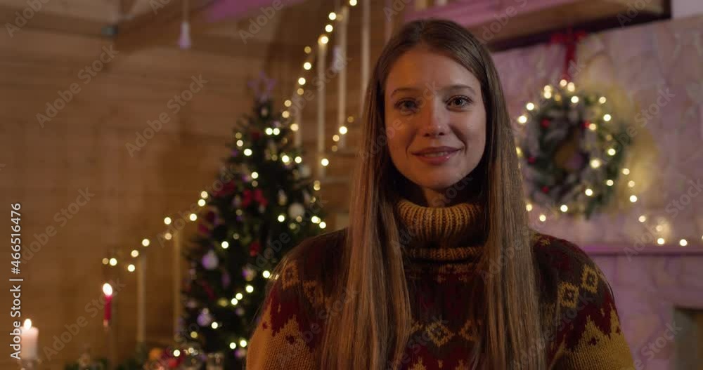 Portrait of Pretty Adult Girl standing at Home with Christmas Tree on background. Happy Female Celebrating Holidays at Home. Looking into Camera with Smile. Holiday Mood. New Year. Christmas. Portrait of Pretty Adult Girl standing at Home with Christmas Tree on background. Happy Female Celebrating Holidays at Home. Looking into Camera with Smile. Holiday Mood. New Year. Christmas.