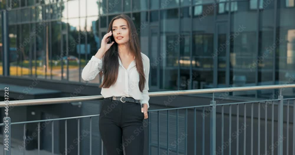 Company secretary dials phone number, calls friend, boss on break, woman stands in front of glass building of corporation, learns good news, happy, cheer, laughter, joy Company secretary dials phone number, calls friend, boss on break, woman stands in front of glass building of corporation, learns good news, happy, cheer, laughter, joy