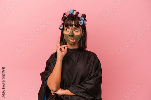 Young mixed race woman waiting in a Beaty salon isolated on pink background confused, feels doubtful and unsure. © Asier