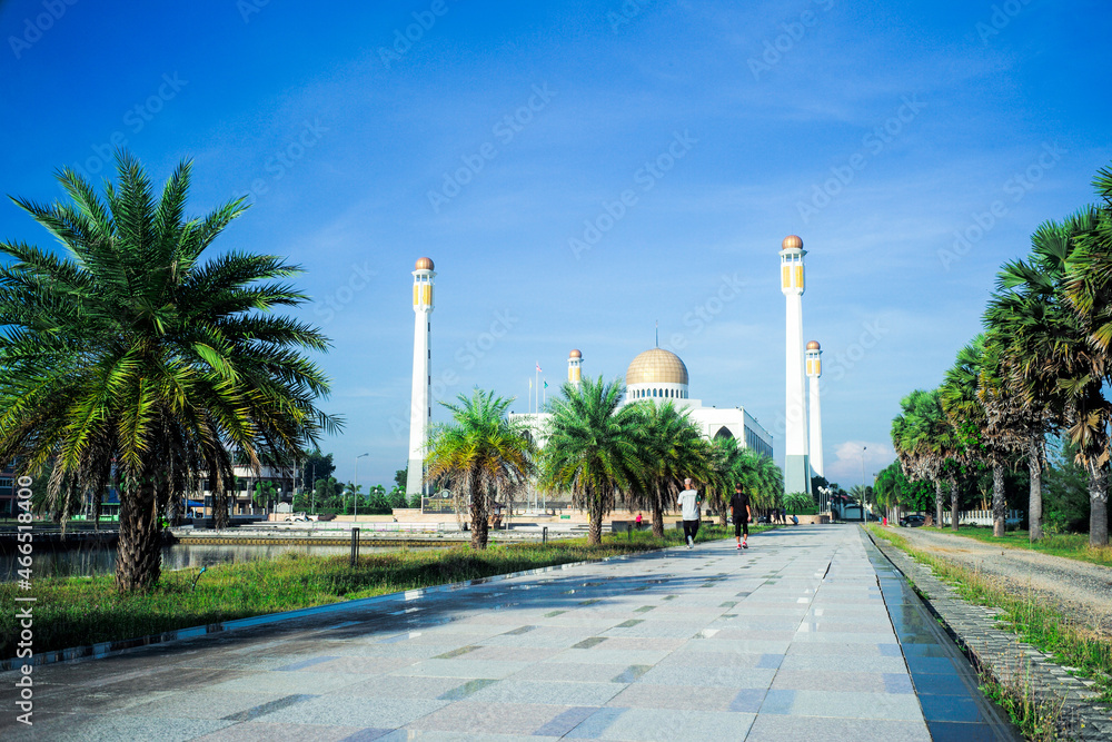 People jogging around the lake with the grand mosque and clear sky in background