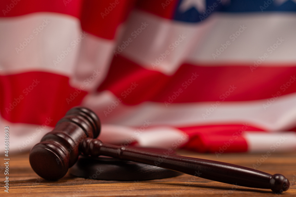 Wooden judge gavel and soundboard on american flag background.