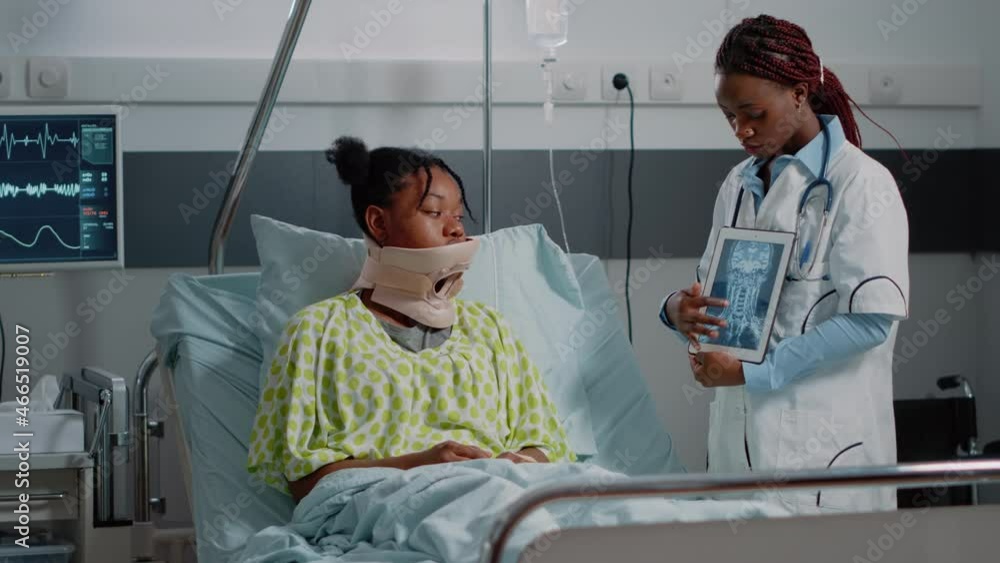 Specialist showing x ray scan to patient with cervical collar laying in