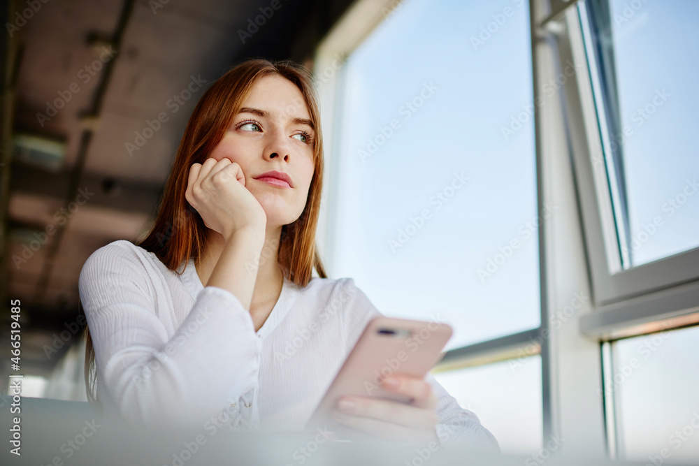 Contemplative female youngster in casual clothes pondering on content idea during network mobility, Caucasian blogger with modern cellphone gadget thoughtful looking away during leisure for phoning Contemplative female youngster in casual clothes pondering on content idea during network mobility, Caucasian blogger with modern cellphone gadget thoughtful looking away during leisure for phoning