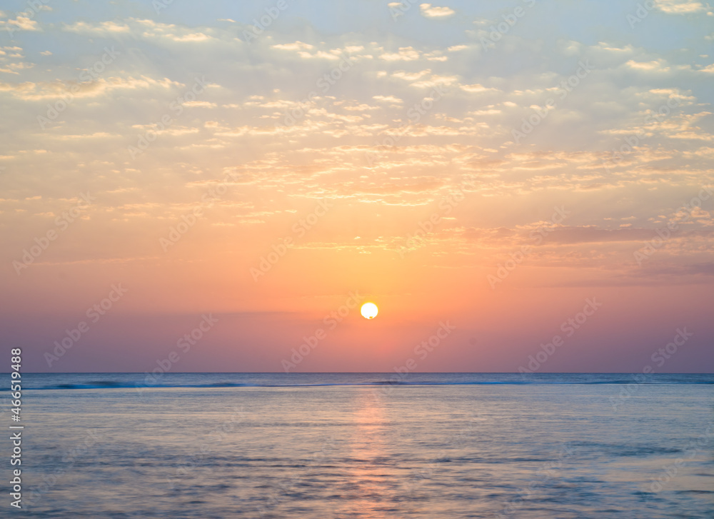 Beautiful sunrise at sea. Dawn on the Red Sea. The sun is reflected in the sea. Light clouds in the blue dawn sky. Tropical sunrise
