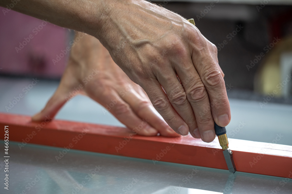 Cutting glass with a special tool. Glass cutter. A master in the