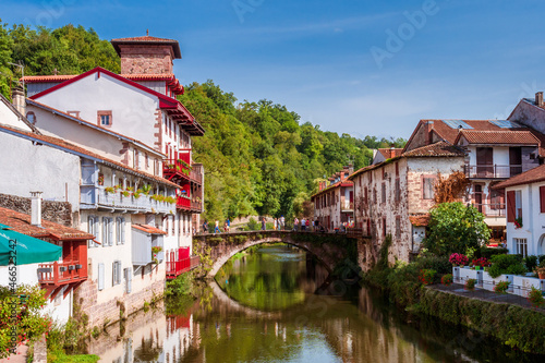 Fototapeta Panoramic view of French white town with red balconies and flowers crossed by a tranquil river