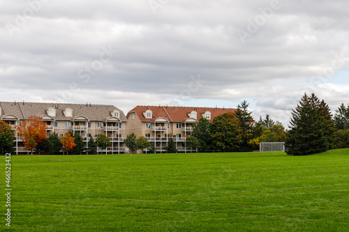 Residential houses near park with green lawn, soccer field and trees in Ottawa city of Canada in fall