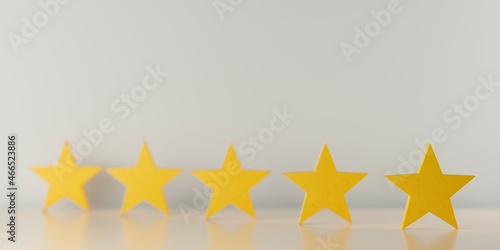 Five yellow wooden stars on table in row with selective focus, five star review for best service or product quality concept