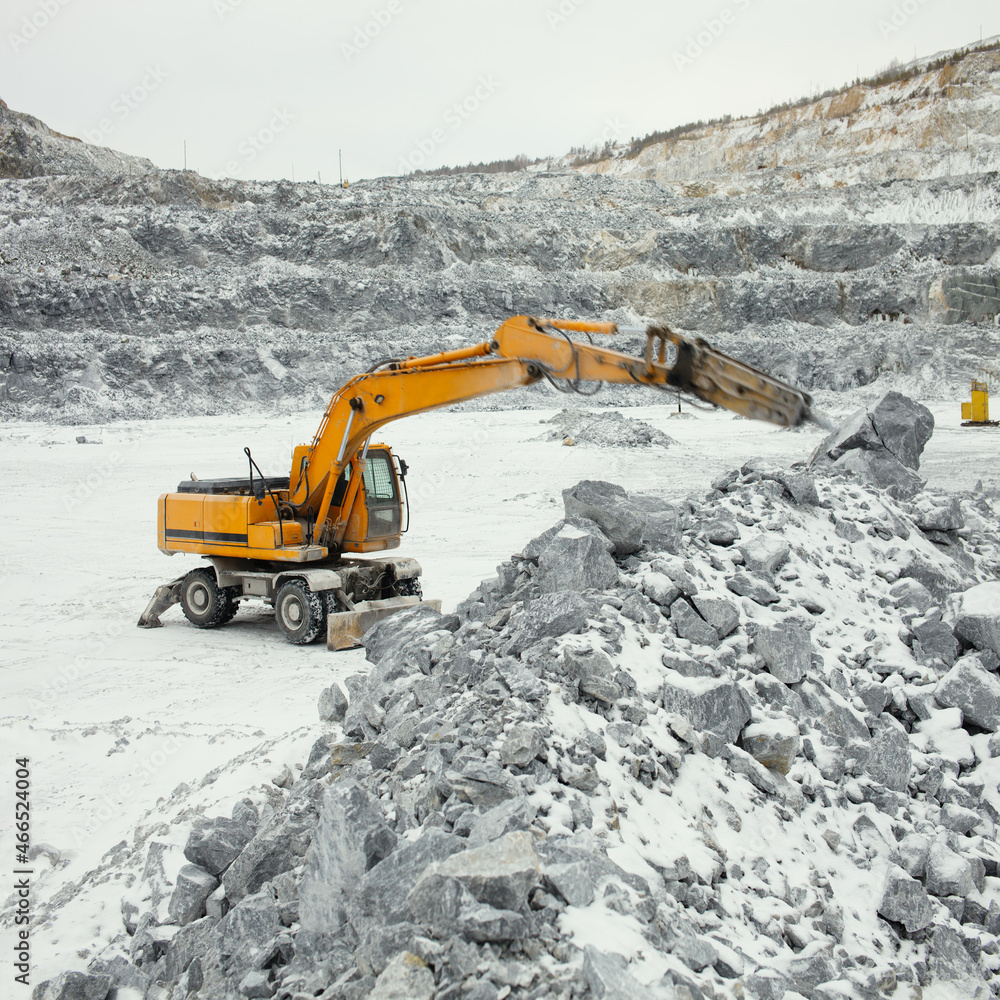 Hydraulic hammer at work in a limestone quarry on a winter cloudy day, square panorama. Hydraulic hammer at work in a limestone quarry on a winter cloudy day, square panorama.