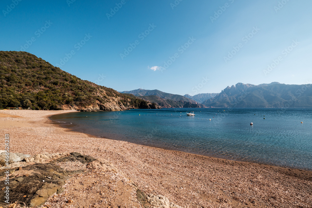 Plage de Gradelle beach in Corsica with the tower of Porto and mountains in the distance