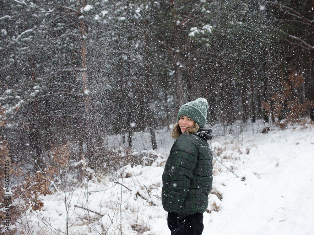 teenage girl in a good mood stands in the forest in winter, snowflakes are flying, snowfall teenage girl in a good mood stands in the forest in winter, snowflakes are flying, snowfall