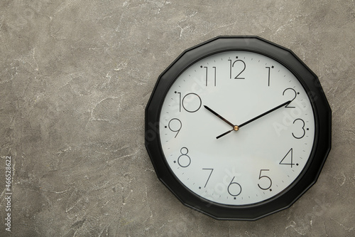 Black wall clock on the grey background.