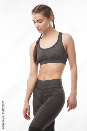Athletic girl in gray clothes for sports and fitness on a white studio background. © pridneprovskiy