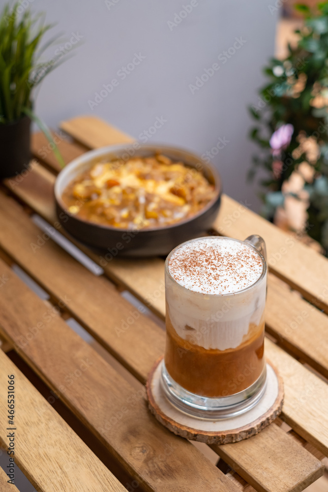 Cappuccino coffee in a transparent cup on a wooden table with nature background Cappuccino coffee in a transparent cup on a wooden table with nature background