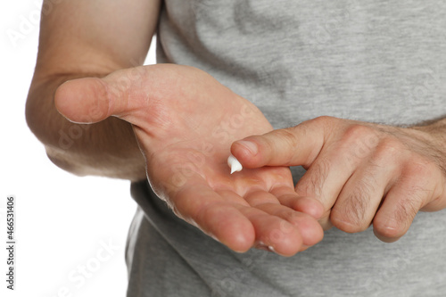 Man applying cream on hand for calluses treatment against white background, closeup