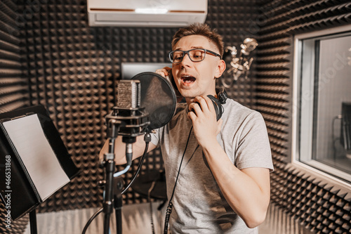 The vocalist sings in the studio in a microphone. Man in headphones writes a podcast, an audiobook. Artist, recording an album, working with the label. Announcer records a speech at a radio station photo