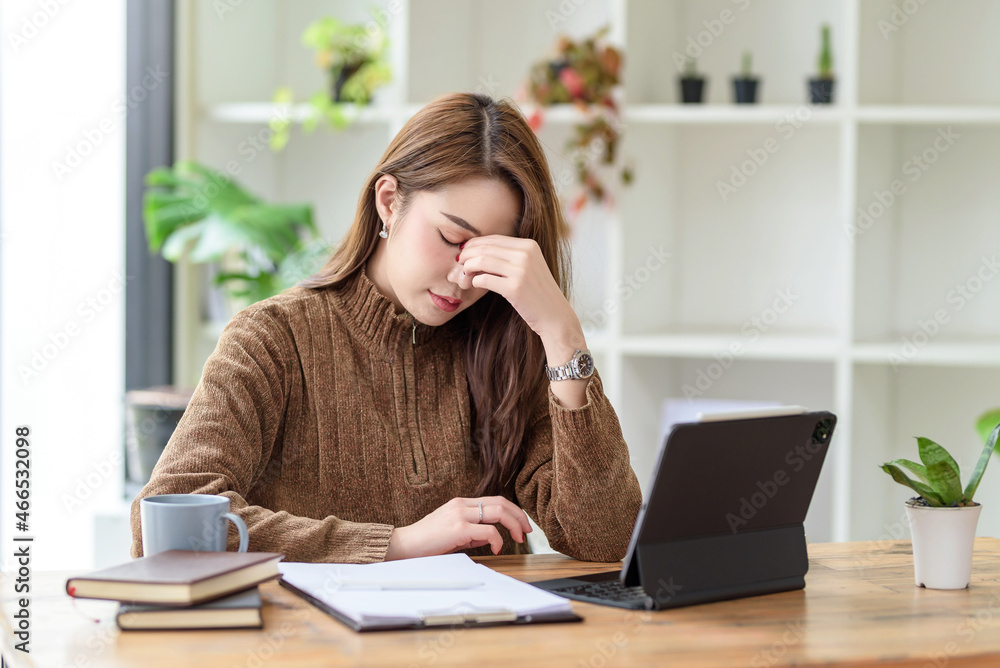 Young Asian woman feeling migraine head strain. Tired, Overworked businesswoman financier while working on laptop computer in office. Young Asian woman feeling migraine head strain. Tired, Overworked businesswoman financier while working on laptop computer in office.