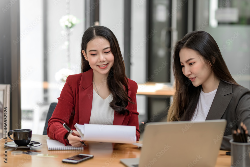 Teamwork of two Asian business women analyzes, discusses plan for collaboration in the office. Teamwork of two Asian business women analyzes, discusses plan for collaboration in the office.