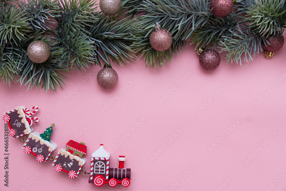 Christmas tree branch decorated with Christmas balls and a toy train. New Year card, top view, flat lay.