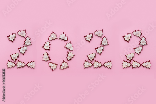 Number 2022 from wooden Christmas trees isolated on pink background.