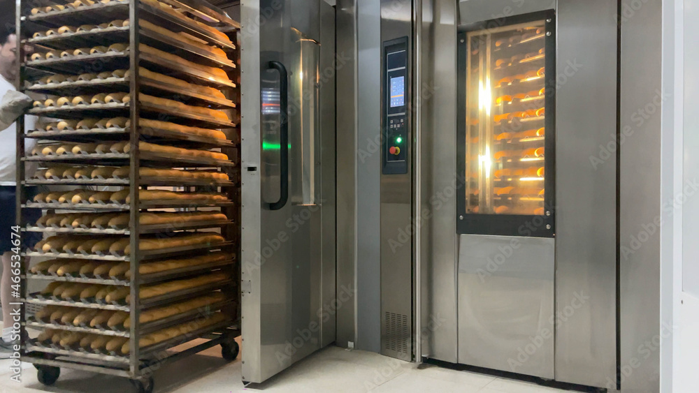 Baker taking fresh bread out of the oven. Fresh bread coming out of the industrial oven. Concept baker, bread, machine, industry, factory, bakery. Baker taking fresh bread out of the oven. Fresh bread coming out of the industrial oven. Concept baker, bread, machine, industry, factory, bakery.