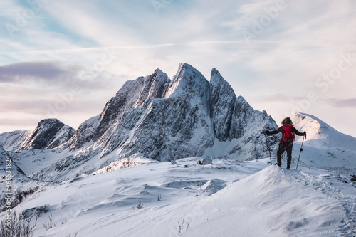 Mountaineer standing on Segla mountain with majestic snowy mount on winter at Senja island
