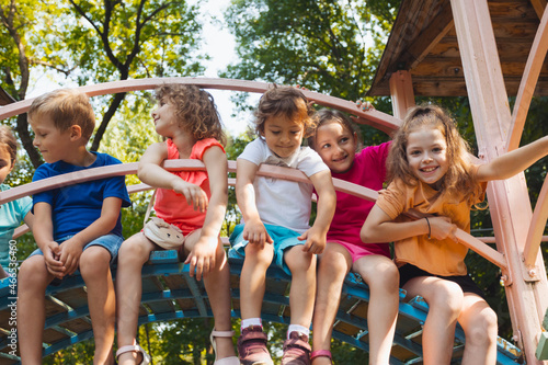 The cute kids are resting in the playground in summer