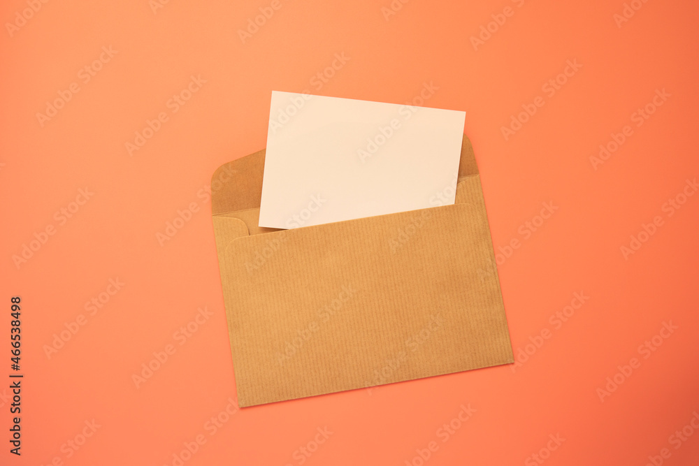 Craft paper envelope with white note blank on pink background Craft paper envelope with white note blank on pink background